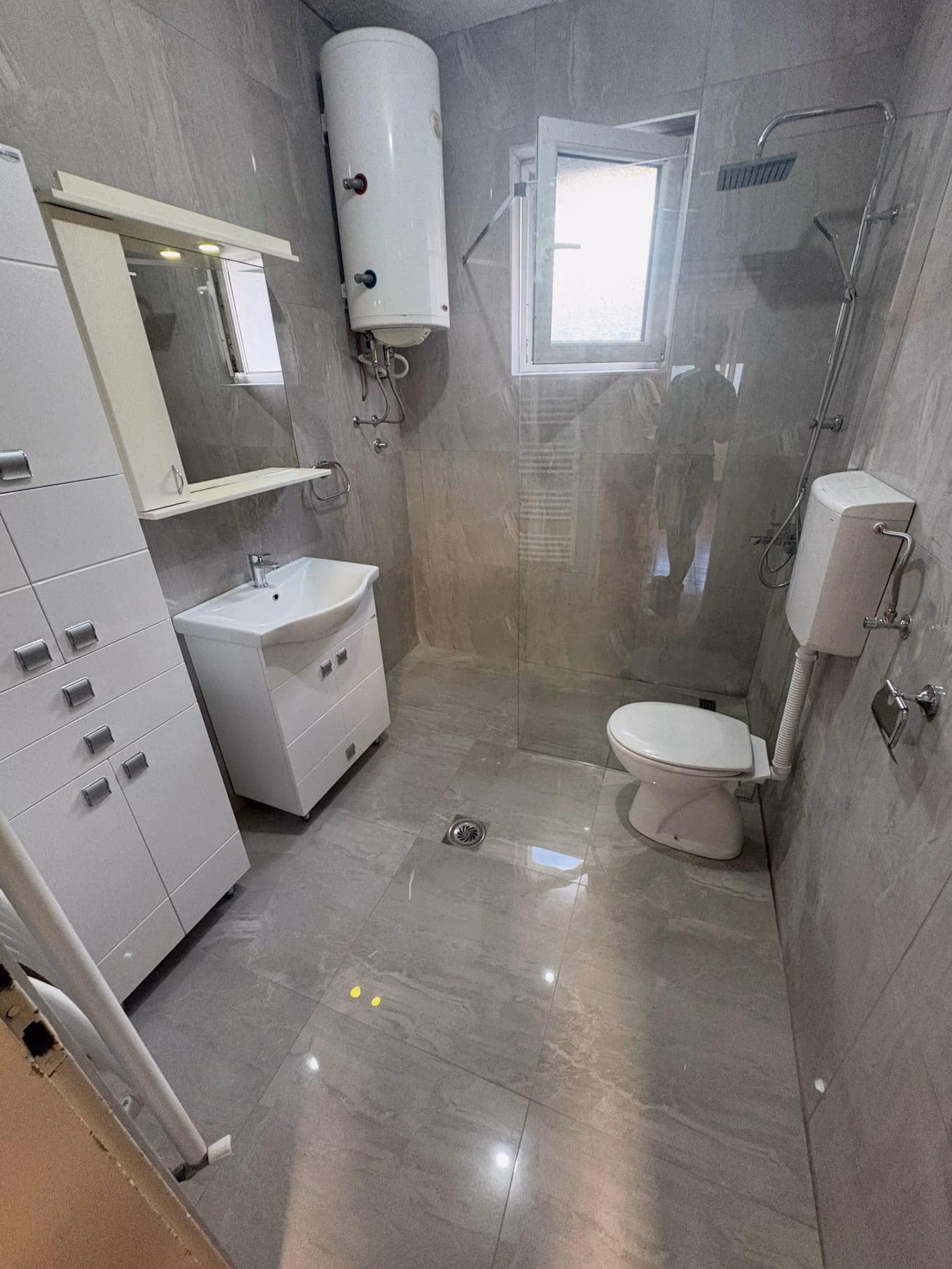 Završeno kupatilo u sivom mermernom dekoru — walk-in tuš sa staklenom pregradom
